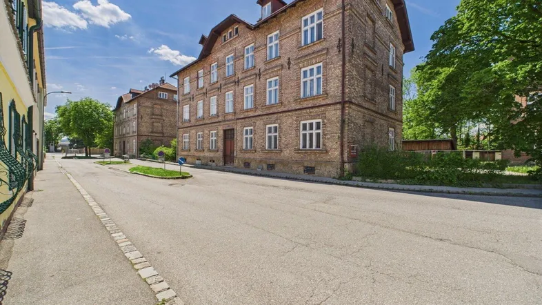 Mehrfamilienhaus aus Ziegelstein mit traditioneller Architektur an einer ruhigen Straße.