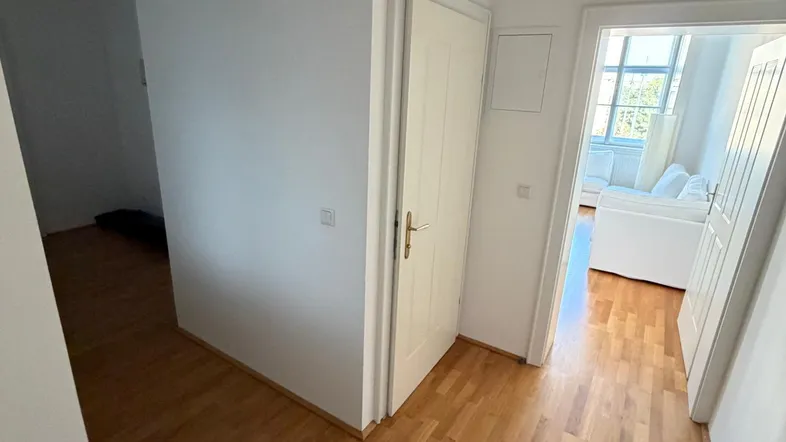 Heller Flur mit Holzfußboden und Zugang zu verschiedenen Räumen, gut beleuchtet durch natürliches Licht.