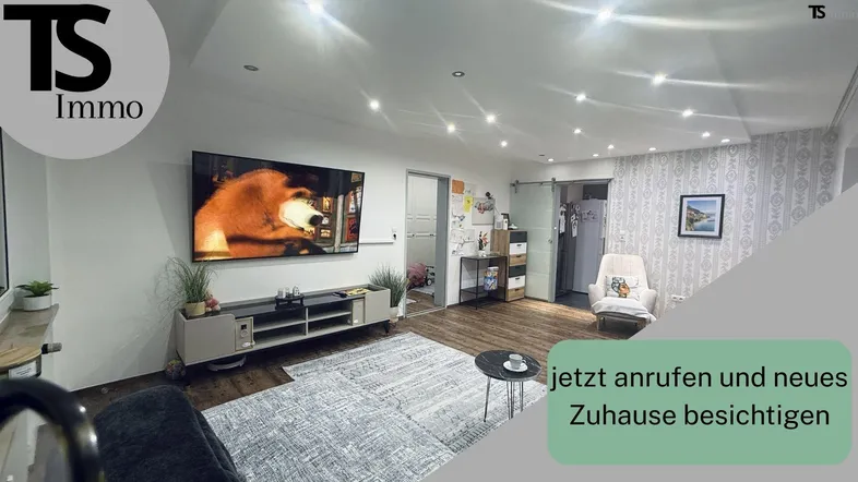 Helles Wohnzimmer mit großem Fernseher, moderner Beleuchtung und gemusterten Tapeten.
