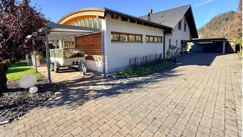 Seitenansicht des Hauses mit gepflasterter Auffahrt und überdachtem Carport.