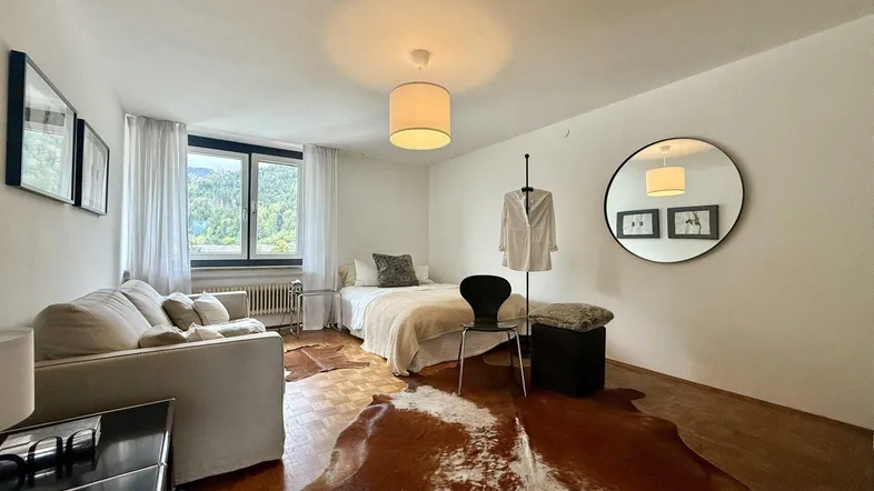 Helles Schlafzimmer mit Parkettboden, Sofa und Blick auf die Berge.