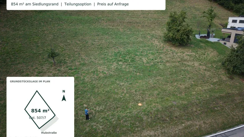 Luftaufnahme eines grünen Baugrundstücks mit 854 m² am Siedlungsrand, umgeben von Bäumen und Häusern.