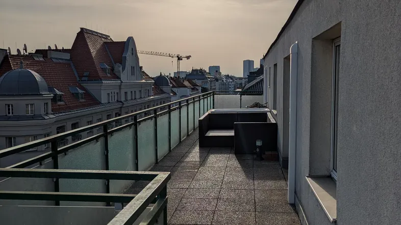 Große Dachterrasse mit Fliesenboden, Geländer und einem Whirlpool, bietet einen weiten Blick über die Stadt.