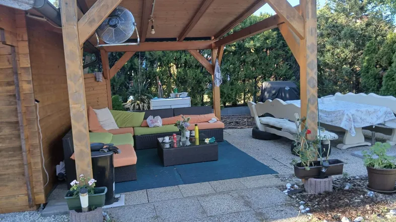 Überdachte Terrasse mit gemütlicher Sitzecke und Blick ins Grüne, ideal für entspannte Stunden im Freien.