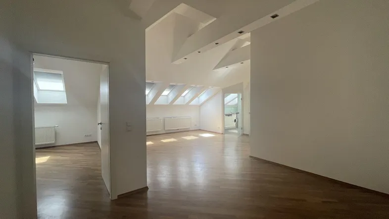 Helles und geräumiges Dachgeschoss-Wohnzimmer mit Holzboden und vielen Dachfenstern.