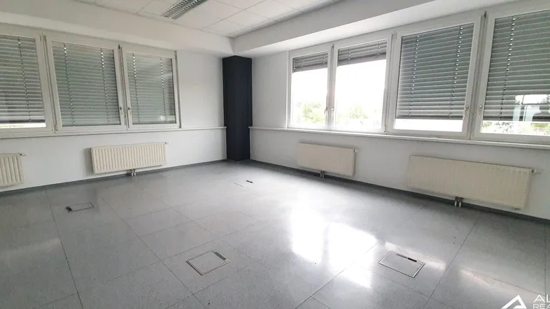 Geräumiges Büro mit großen Fenstern, Jalousien und Heizkörpern, bereit zur individuellen Gestaltung.