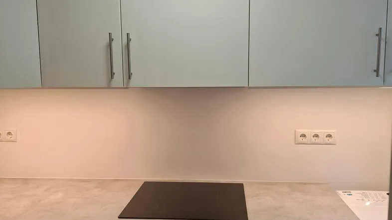 Moderne Küche mit weißen Hochglanzfronten, Induktionskochfeld und integriertem Backofen.