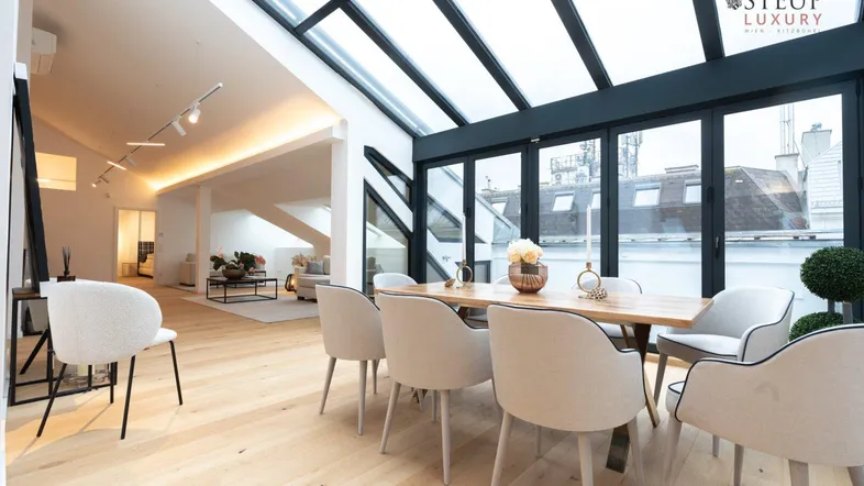 Geräumiger, lichtdurchfluteter Wohn- und Essbereich mit Holzboden und großer Glasfront zum Dach.