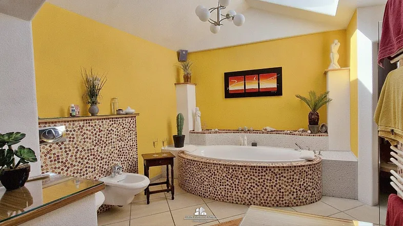 Geräumiges Badezimmer mit großer Badewanne, Bidet und farbenfrohen Mosaikfliesen an den Wänden.