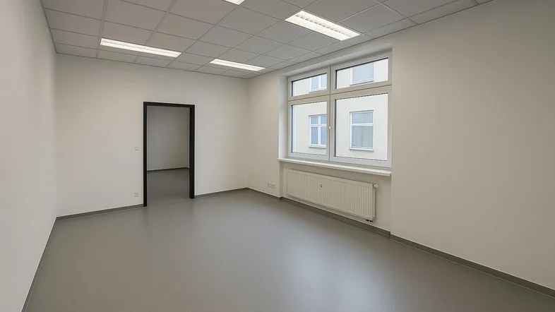 Heller, leerer Büroraum mit großen Fenstern, abgehängter Decke und grauem Vinylboden.