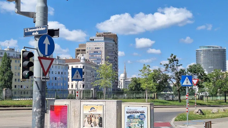 Blick auf die städtische Umgebung mit Gebäuden, Verkehrsschildern und blauem Himmel an einem sonnigen Tag.