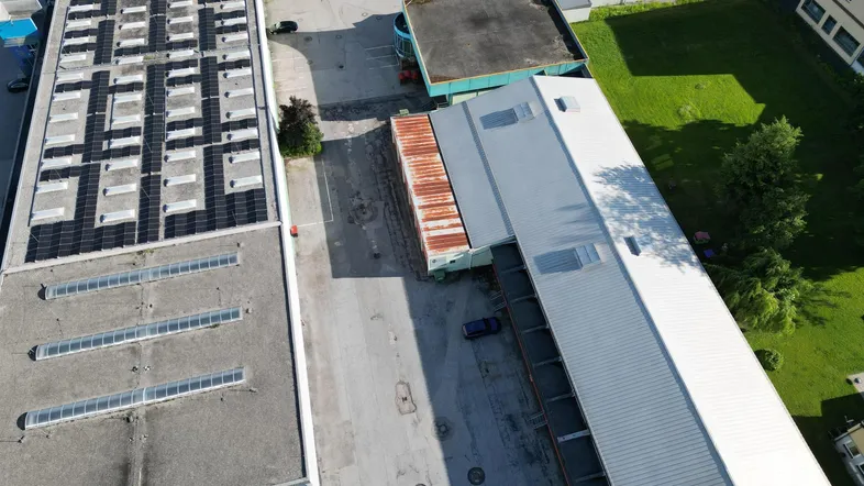 Luftaufnahme eines Industriegebiets mit mehreren Gebäuden, Parkplätzen und Solaranlagen auf einem Dach.
