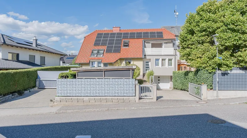 Ansicht des Hauses von der Straße mit Photovoltaikanlage auf dem Dach und gepflegtem Vorgarten.