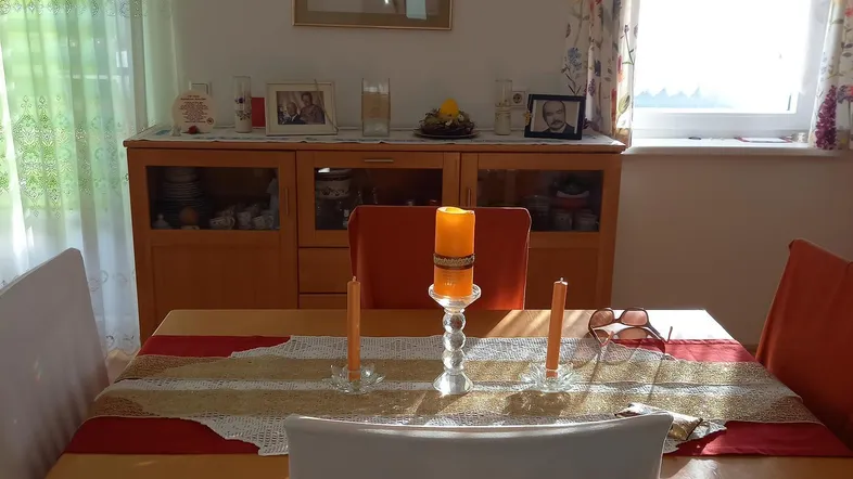 Gemütlicher Essbereich mit Holztisch, Stühlen und einem Sideboard, hell durch Fenster.