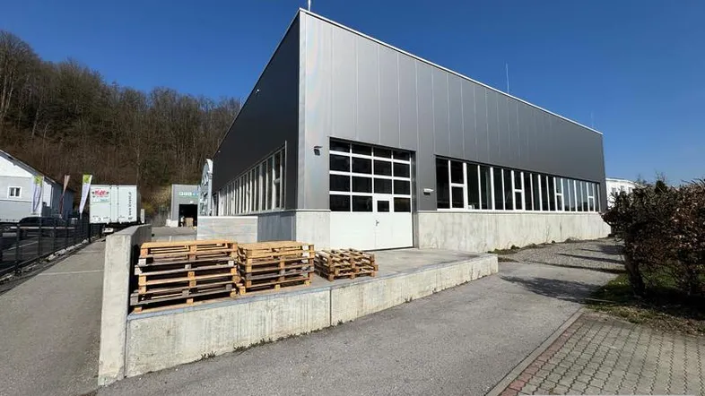 Modernes Industriegebäude mit Metallfassade und Laderampe unter blauem Himmel.