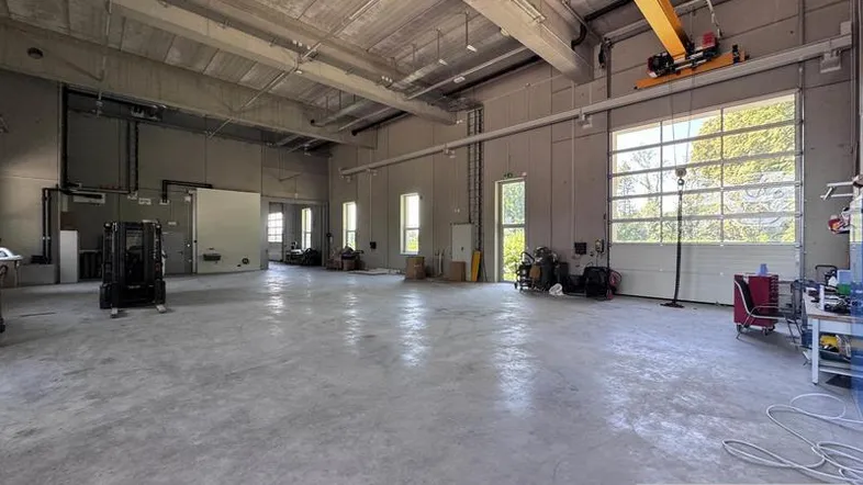 Geräumige Lagerhalle mit hohen Decken, Betonboden und großen Fenstern, ausgestattet mit einem Kran.
