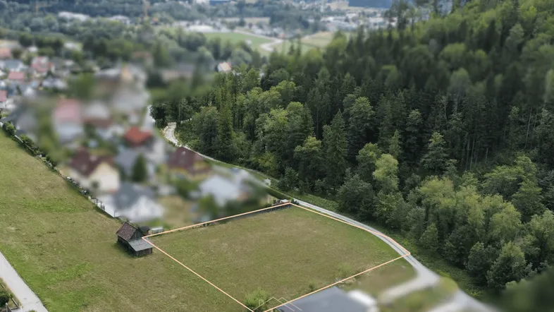 Luftaufnahme eines Baugrundstücks mit Umriss und kleiner Hütte in ländlicher Umgebung.