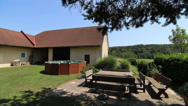 Großer Gartenbereich mit Rasenfläche, Sitzgelegenheiten und einem kleinen Aufstellpool, umgeben von Natur.