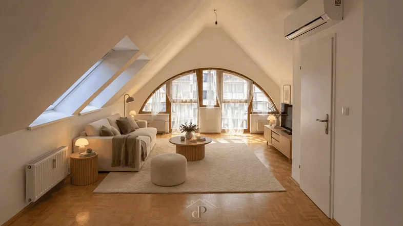 Helles, modern eingerichtetes Wohnzimmer im Dachgeschoss mit großen Fenstern und Holzboden.