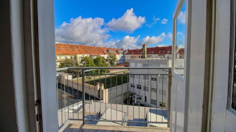 Blick vom Balkon auf die umliegenden Gebäude und den blauen Himmel der Stadt.