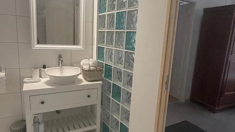 Modernes Badezimmer mit Waschbecken, Spiegel und dekorativer Glasbausteinwand.
