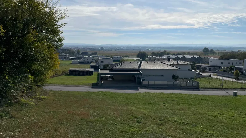 Panoramablick von einem erhöhten Grundstück auf eine ländliche Wohnsiedlung und weite Landschaft.