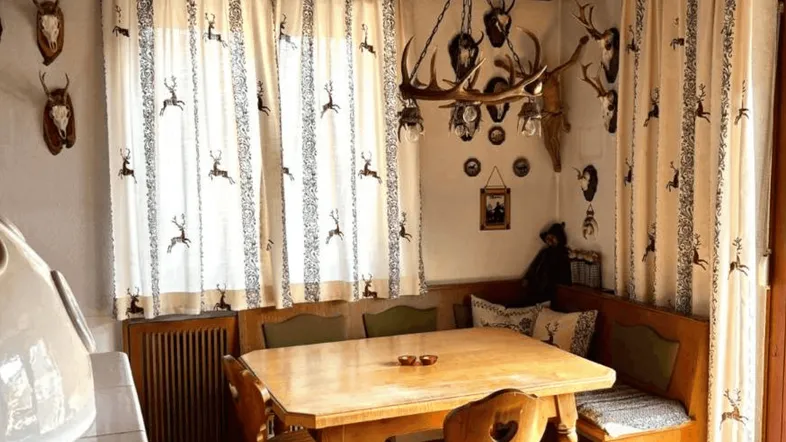 Traditioneller Essbereich im alpinen Stil mit Holztäfelung, Kassettendecke und Hirschgeweih-Dekoration.