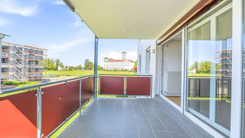 Geräumiger Balkon mit Fliesenboden und weitem Blick auf die Umgebung und ein historisches Gebäude.