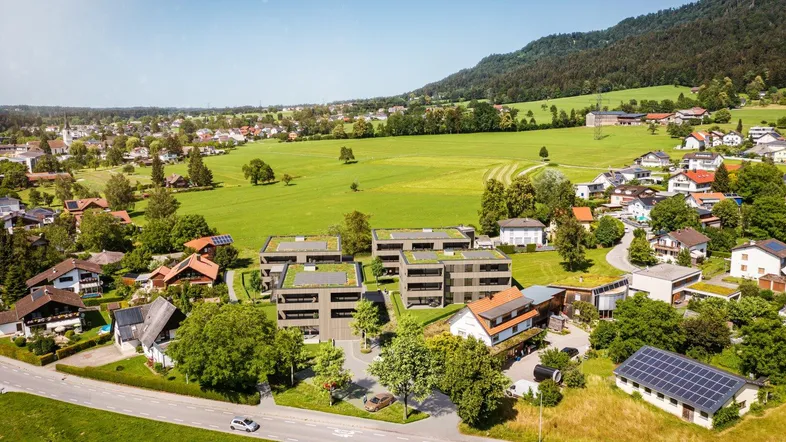 Luftaufnahme einer modernen Wohnanlage mit Gründächern und ländlicher Umgebung.