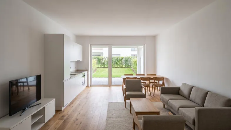 Helles, offenes Wohn-Esszimmer mit integrierter Küche, Holzboden und Zugang zum Garten.