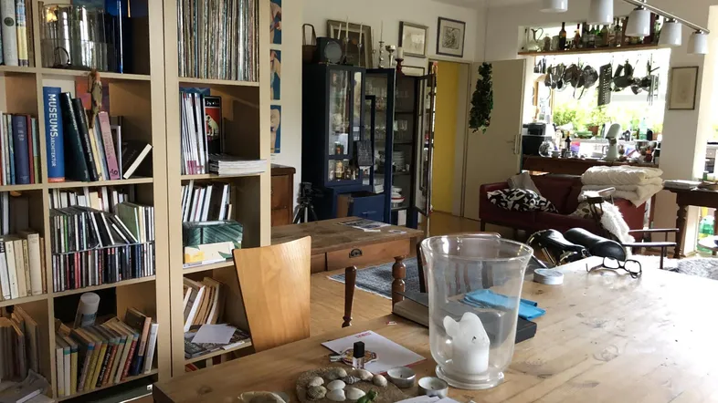Geräumiger Wohn-Essbereich mit Bücherregalen, Holztisch und Blick in den angrenzenden Raum.