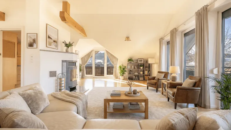 Helles und geräumiges Wohnzimmer mit Kamin, bequemen Sofas und Zugang zum Balkon mit Bergblick.