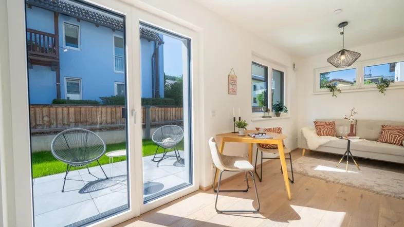 Heller Wohn- und Essbereich mit Holzboden, großen Fenstern und Zugang zur Terrasse.
