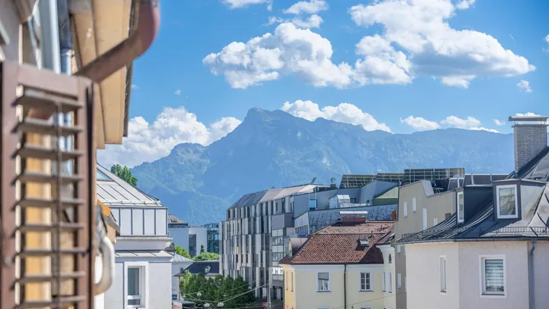 Panoramablick auf die Berge und die Stadt von einem Balkon oder Fenster unter blauem Himmel.