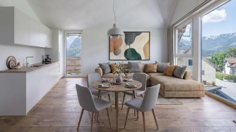 Helles, offenes Wohn-Esszimmer mit integrierter Küche, Holzboden und beeindruckendem Bergblick.