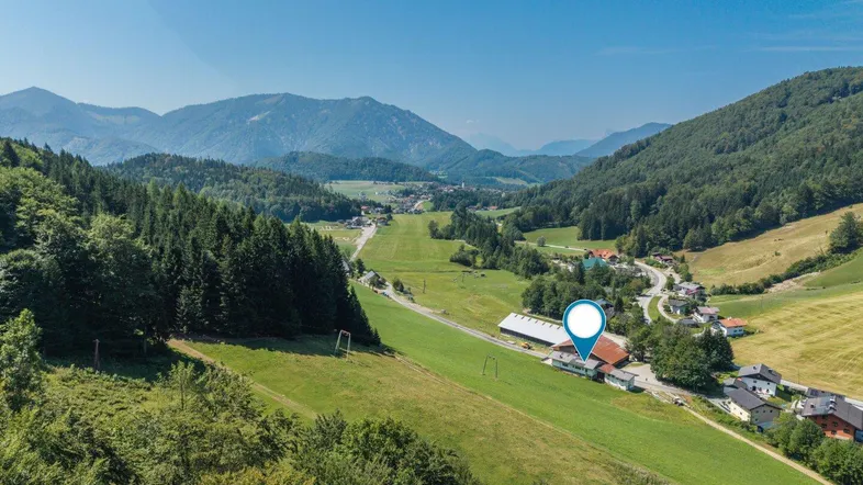 Panoramablick auf die umliegende Berglandschaft und grüne Täler mit einem markierten Standort.