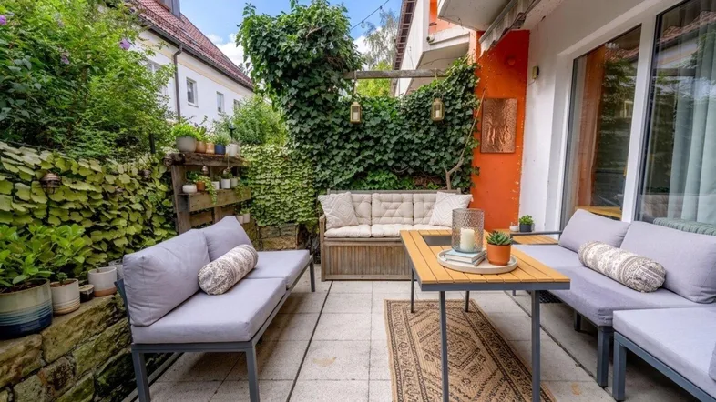 Gemütliche Terrasse mit bequemen Sitzmöbeln und üppiger Begrünung, ideal zum Entspannen im Freien.