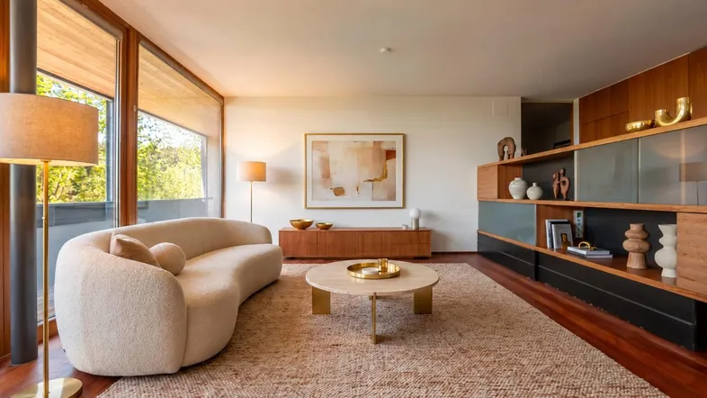Helles Wohnzimmer mit modernem Sofa, Holzboden und integriertem Regal mit Dekoration.