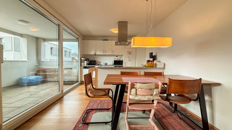 Moderne Küche mit Essbereich, Holzboden und Zugang zu einem großen Balkon.
