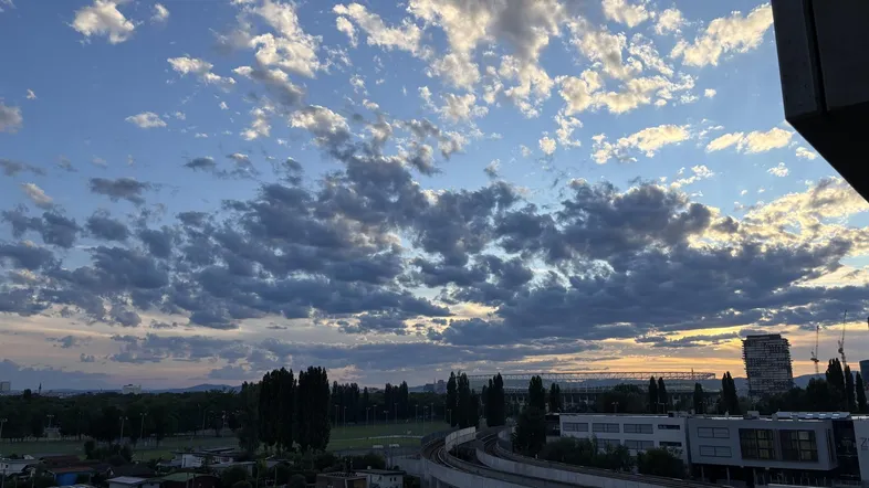 Malerischer Sonnenuntergang über der Stadt mit weiten Ausblicken auf Gebäude und Grünflächen.