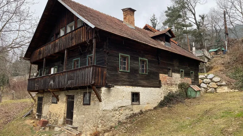 Rustikales Holzhaus mit traditionellem Satteldach und Balkon in ländlicher Umgebung.