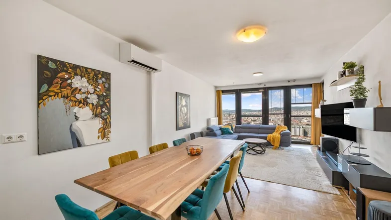 Heller Wohn- und Essbereich mit Holztisch, bequemer Couch und weitem Stadtblick.