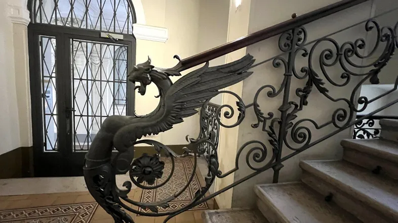 Historisches Treppenhaus mit kunstvollem schmiedeeisernem Geländer und verzierten Fliesenböden.