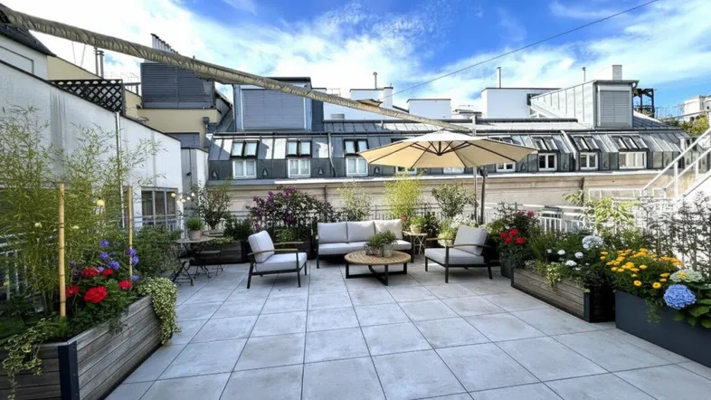 Attraktive Dachterrasse mit Sitzgelegenheiten, Sonnenschirm und vielfältiger Bepflanzung für entspannte Stunden.