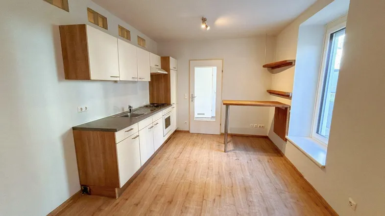 Helle, offene Küche mit Laminatboden, Einbauküche und integriertem Essbereich am Fenster.