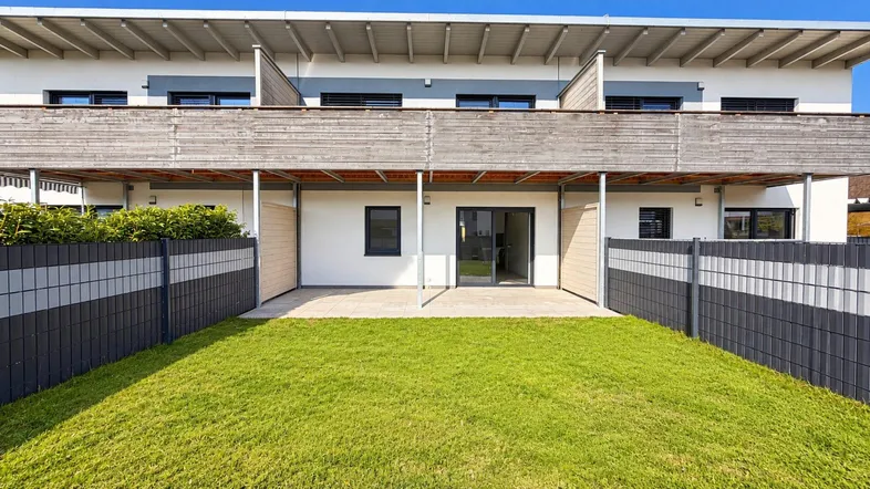 Moderne Reihenhausfassade mit privatem Gartenbereich und Terrasse im Erdgeschoss.