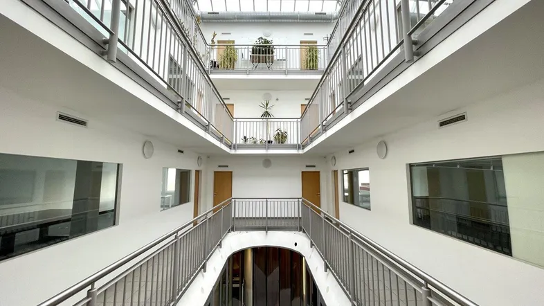 Heller, mehrstöckiger Innenhof mit Glasdach und umlaufenden Galerien, die zu den Büros führen.