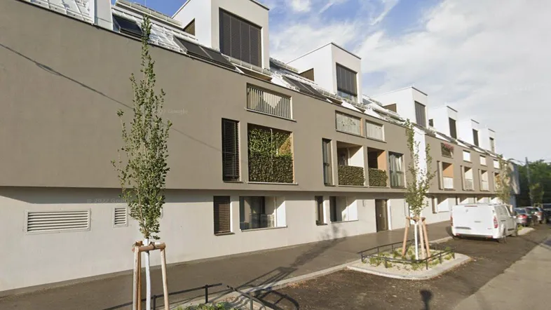 Moderne Wohnanlage mit beiger Fassade, großen Fenstern und begrünten Balkonen.