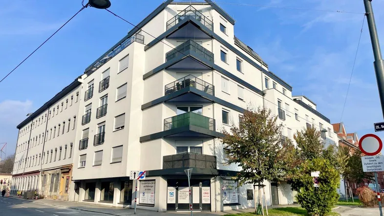 Modernes Eckgebäude mit mehreren Etagen und Balkonen an einer städtischen Straße.