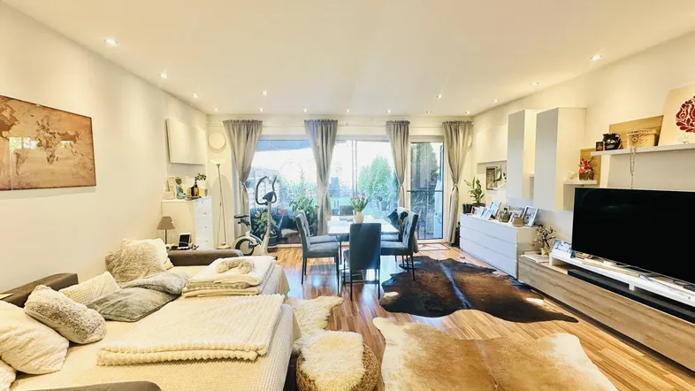Helles Wohn- und Esszimmer mit Holzboden, gemütlichem Sofa und Zugang zur Terrasse.